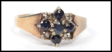 A hallmarked 9ct gold diamond and sapphire cluster ring having five sapphires with four diamonds