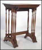 An Edwardian oak nest of tables being raised on turned column supports with splayed legs having