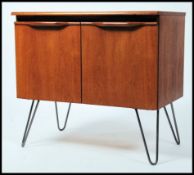 A 1970's retro teak wood 2 door cabinet being raised on tapered hairpin legs, each cabinet door with