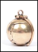 A 9ct gold and silver metamorphic pendant in the form of a ball opening to reveal an inset cross