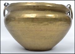 An early 20th century arts and crafts brass bowl / planter having a planished design with twin