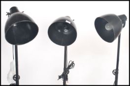 A group of three vintage retro industrial style metal tubular tripod floor  spot lamp, having an
