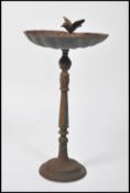 A vintage 20th century cast iron pedestal bird bath. The scalloped shaped bath surmounted with a