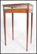 An Edwardian mahogany bijouterie display cabinet table being raised on sqaure tapered legs with