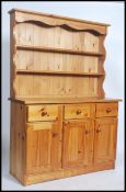 A 20th century pine dresser having a series of cupboards below drawers with a shelved dresser top
