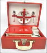 A vintage retro 20th century Brexton portable picnic hamper set in a red vinyl case with fitted