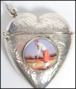 A sterling silver vesta case in the form of a heart with inset golfing cameo having a chased