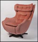 A 1960's Parker Knoll large batwing swivel egg chair - armchair being raised on a teak quadruped