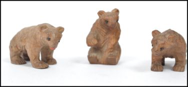 A group of three miniature black forest carved wooden bears in varying positions. Highest measures 4