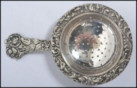 A silver 90 marked early 20th century tea strainer of rococo form having  rococo castins of