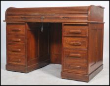 A 1920s oak kneehole twin pedestal roll top desk, the S shaped tambour roll enclosing a fitted