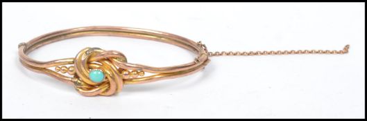 A 9ct gold stamped two strand knot bracelet bangle having a central turquoise stone. Weighs 7