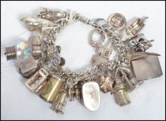 A hallmarked silver charm bracelet having many charms to include a shoe, phone box, man playing