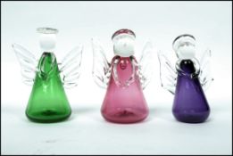 A group of three Bristol Blue Glass angels in peridot, amethyst and cranberry colour ways complete