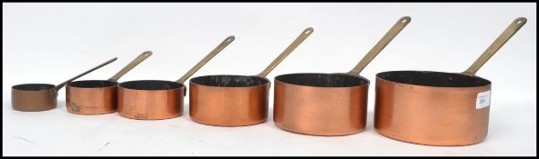 An early 20th century set of copper  saucepans fitted with riveted brass handles of graduating