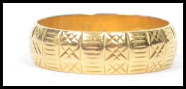 A hallmarked 18ct gold band ring having a geometric engraved design.