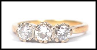 A hallmarked 18ct gold three stone diamond ring, the three prong set stones set to a yellow band