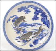 A vintage 20th century Oriental Ceramic charger plate depicting swimming carp on a white ground