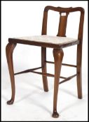 An Edwardian Queen anne mahogany piano chair having and over stuffed seat pad and raised cabriole