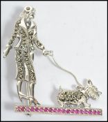 A ladies contemporary silver Art Deco style brooch in the form of a lady walking her dog being inset