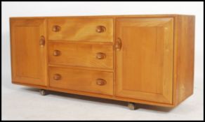 A 20th century light elm and beech wood sideboard by Ercol with three central drawers, the top