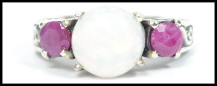 A ladies silver three stone ring with central opal having adjacent garnet prong setting. Size N /