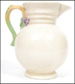 A Clarice Cliff pottery jug of baluster form, shape 895, with painted and moulded floral handle,