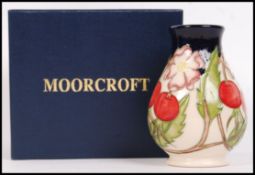 A Moorcroft ceramic tube lined vase decorated in the Rosehip pattern with impressed marks and