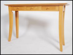 A 20th century Marks and Spencer's beech console table, raised on sabre legs, three drawers under
