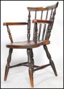 A Victorian beech and elm wood childs windsor armchair being raised on turned legs united by