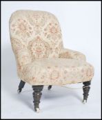 A Victorian nursing chair with tub shaped back, raised on mahogany turned legs, upholstered in a