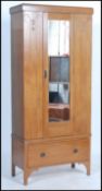 An Edwardian single oak wardrobe, the shaped cornice above a single bevelled mirror door enclosing