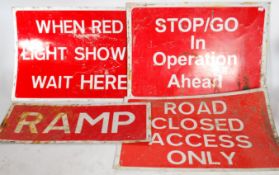 A collection of four retro 20th century metal road work signs, white lettering on red ground reading