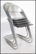 A set of four chrome cantilever stacking chairs having an angular structure , industrial joins and a