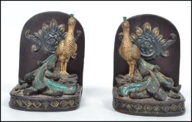 A decorative pair of 20th century gilded and painted resin bookends. Each decorated with peacocks