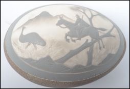 A 19th century carved / etched emu egg having a oval cameo depicting a man on horse hunting an