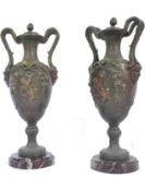 A pair of 19th century spelter painted twin handled urns raised on rouge marble plinth bases. The