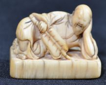A believed 8th century Japanese ivory netsuke in the form of courtesan in repose holding a fan and