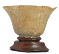 19th century Chinese jade libation cup raised over a wooden socle plinth base. The cup of lozenge