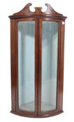 A 19th century bow front mahogany corner display cabinet having a scrolled, inlaid and carved