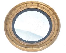 A Regency 19th century gilt plaster and wooden circular convex mirror. The gilt frame with applied