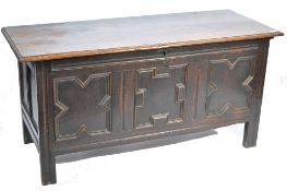 An 18th century carved oak coffer chest raised on bracket feet having a series of fielded
