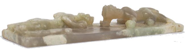 A Chinese jade plaque or scroll weight of rectangular form being carved with 2 fighting dragons,