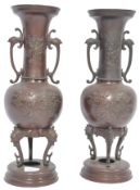 A pair of 19th century Japanese bronze vases raised on stepped circular bases with tripod legs.
