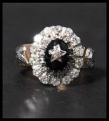 An unusual rose gold diamond and onyx cluster ring  with central oval cut onyx having a diamond