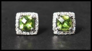 A pair of 925 silver earrings set with a square cut peridot stone surrounded by a halo of CZ