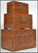 A graduated set of three 20th century Camphor wood boxes, carved panels, hinged lids and brass