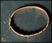 A hallmarked 9ct gold bangle bracelet having a half engraved design with ball finials to top and