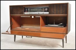 A 1950's retro Grundig laquered walnut radiogram being raised on tapering legs with decorative