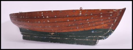 A vintage 20th century painted wood hull model of a clinker - built rowing boat, riveted detail